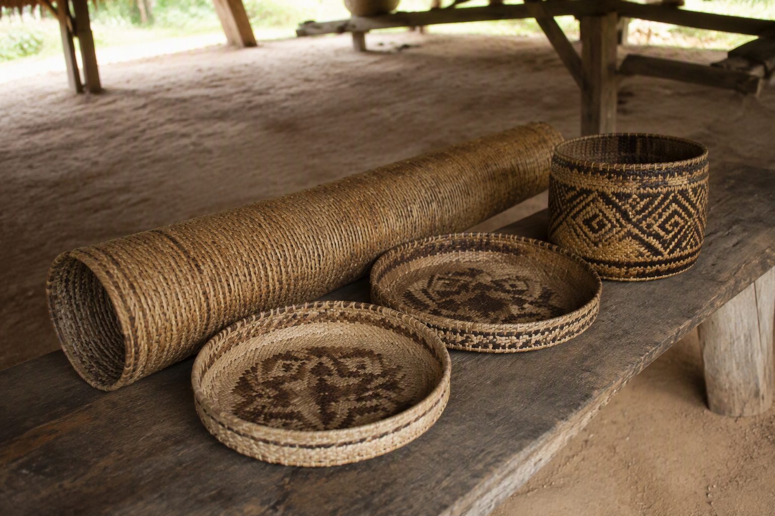Vanneries tressées en fibres végétales posées sur un banc en bois